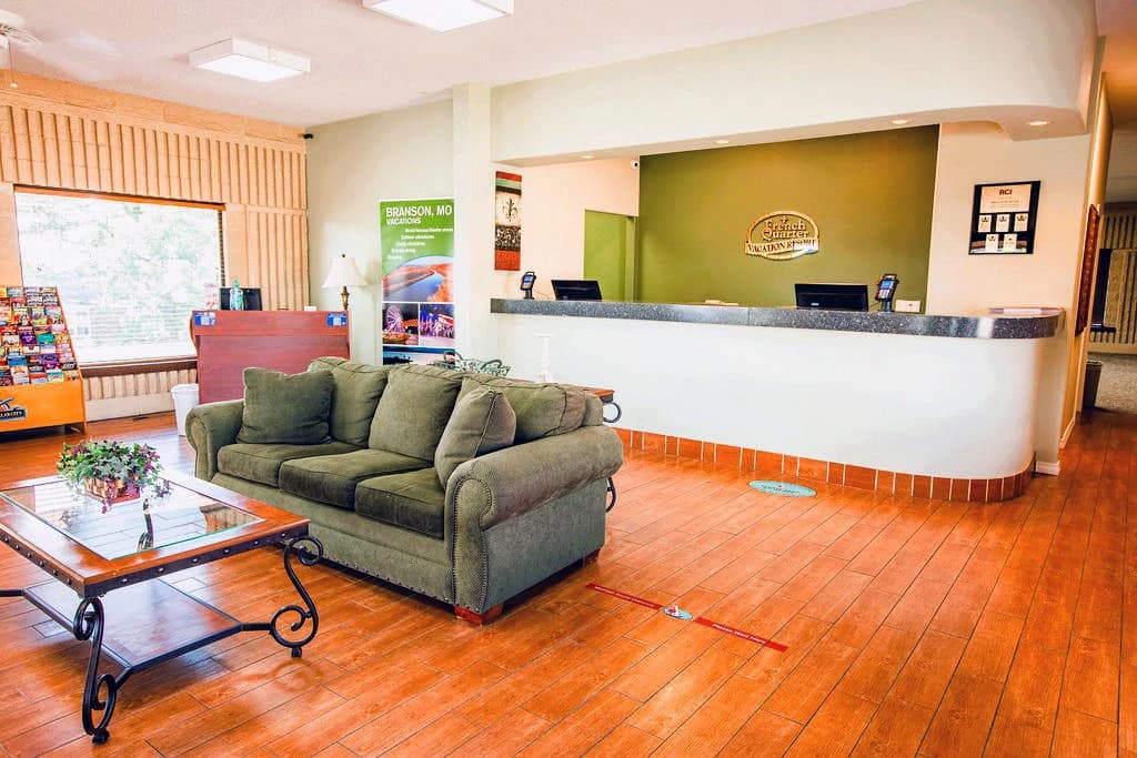 Welcoming lobby with a green sofa, coffee table, and reception desk.